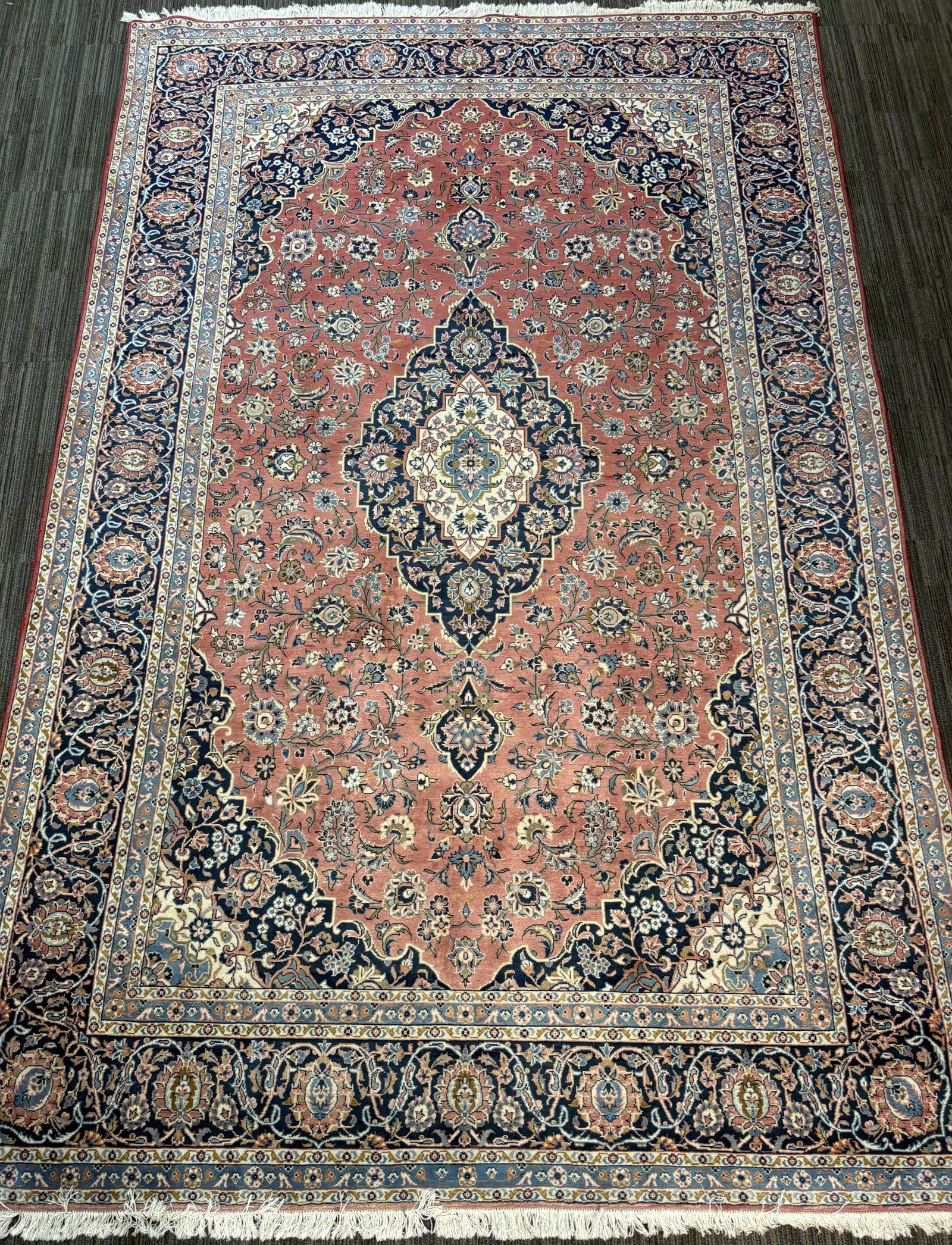 VINTAGE ORIENTAL ROOM SIZE RUG.: A vintage room size rug, featuring a large central floral medallion on a salmon-red field densely decorated with scrolling vines, palmettes, and floral sprays in navy, ivory, pale blue, green, and gol