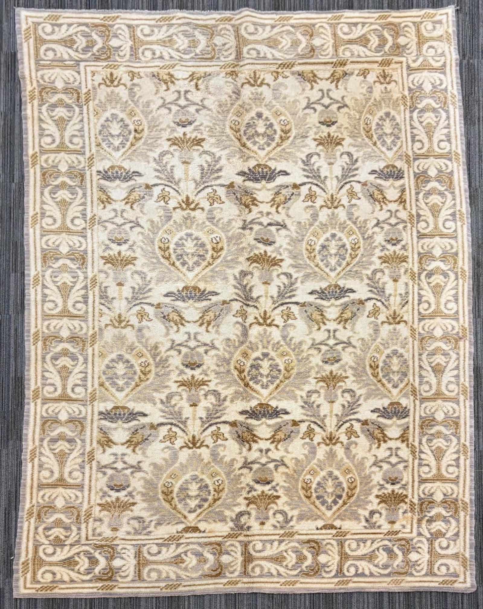 VINTAGE SPANISH ROOM SIZE RUG.: A vintage Spanish decorative area rug with an ivory field featuring stylized floral and pomegranate motifs in muted gold, taupe, gray, and soft blue. 6’ x 8’9”.