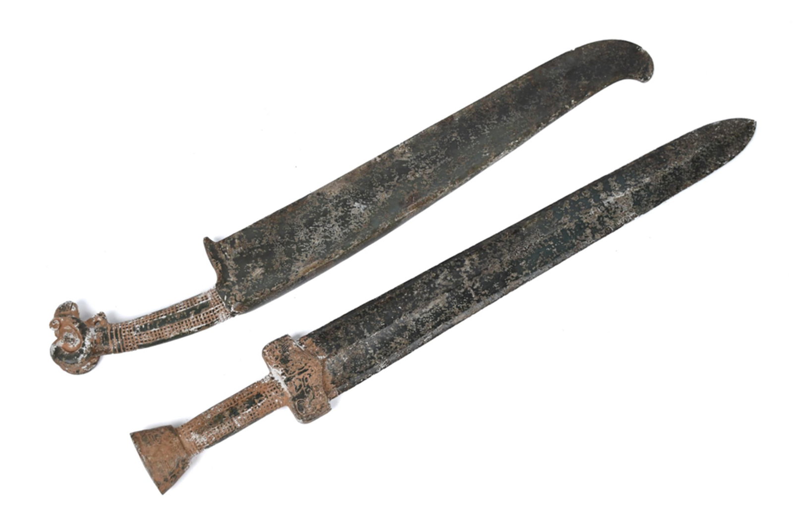 TWO CARVED CHINESE JADE CEREMONIAL SWORDS.: Two 20th C. Chinese jade ceremonial swords, each with a long tapering green jade blade showing heavy surface encrustation and patination throughout. Each with handles decorated in relief having