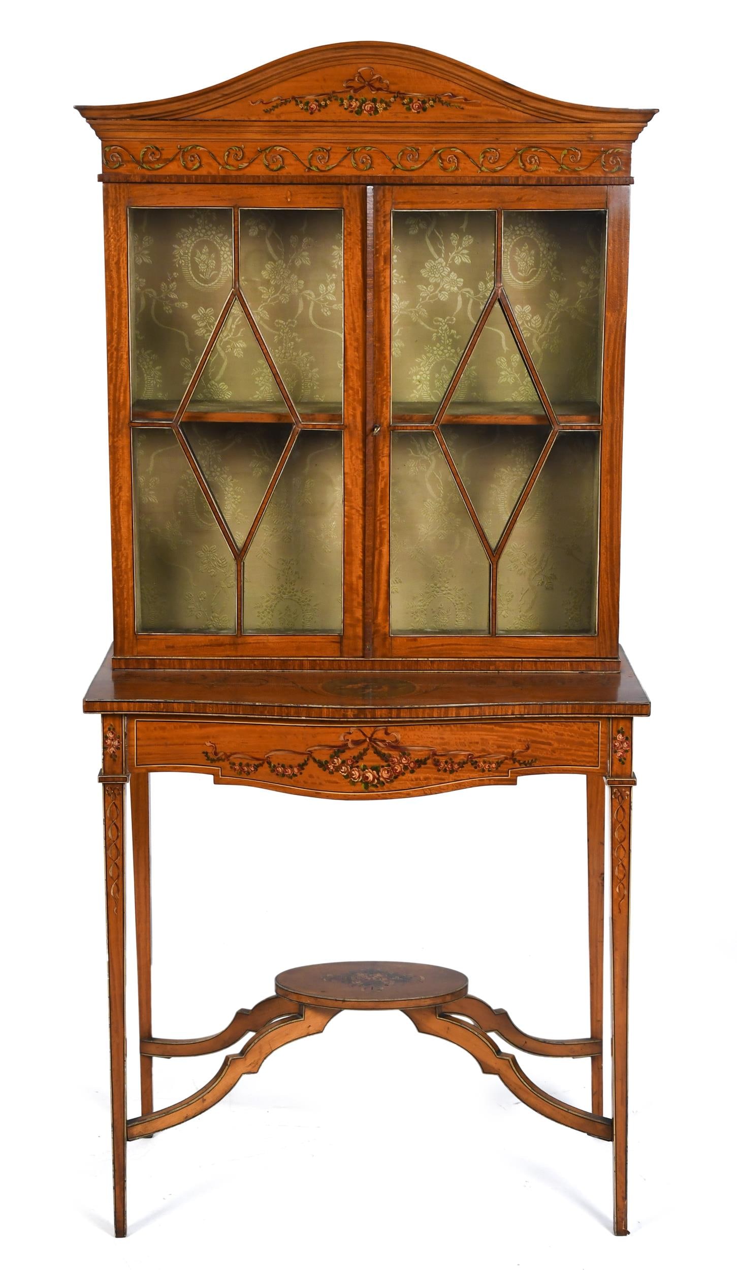 ANTIQUE EDWARDIAN SATINWOOD DISPLAY CABINET.: A ca 1890 English Edwardian satinwood diminutive display cabinet with painted decoration, the arched crest painted with a ribbon and floral swag above a frieze of scrolling foliage, over two astragal