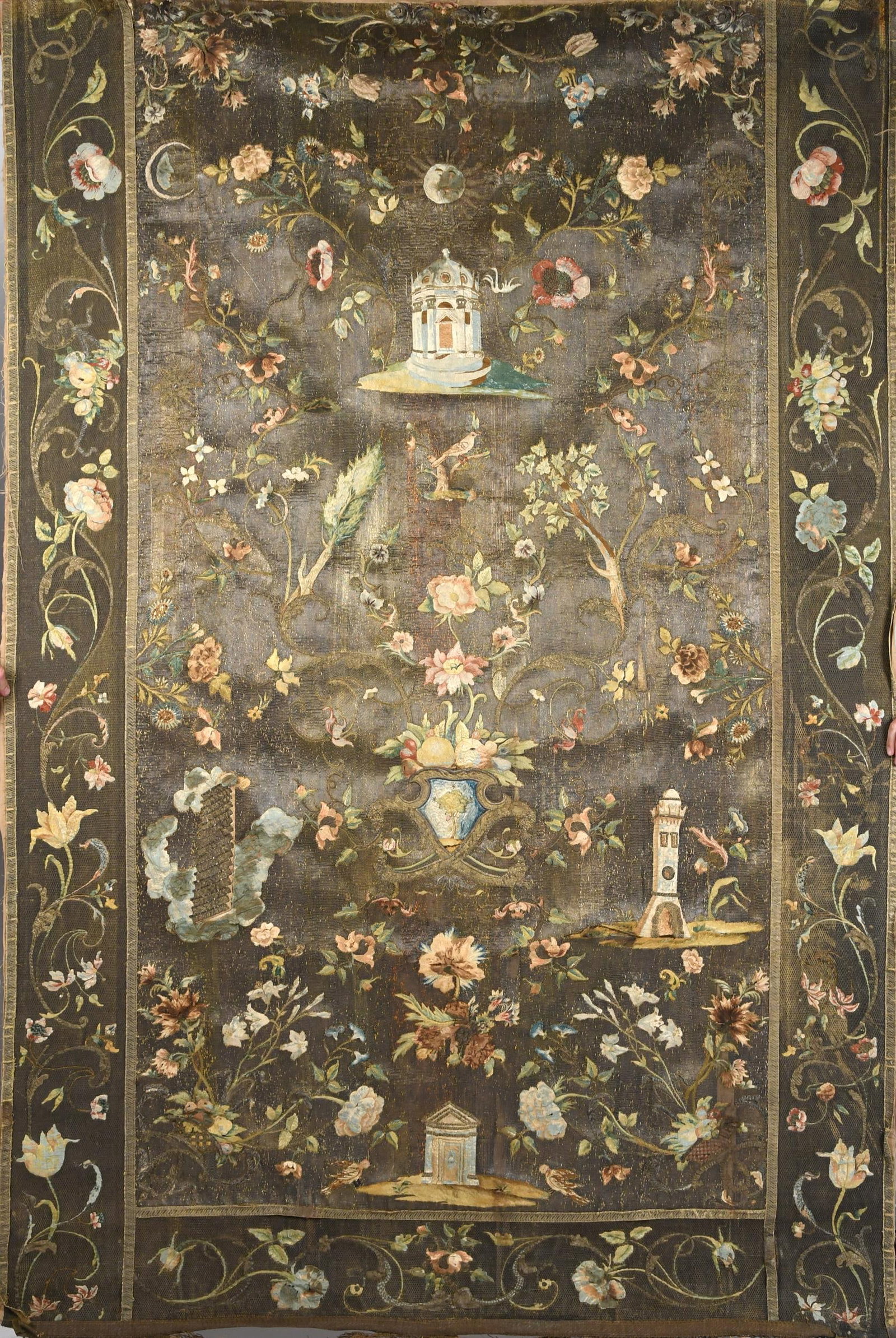 ANTIQUE METALLIC THREAD EMBROIDERED TAPESTRY.: An antique European embroidered wall hanging tapestry, woven with metallic threads, depicting castles, floral motifs and birds. 59” x 86”.