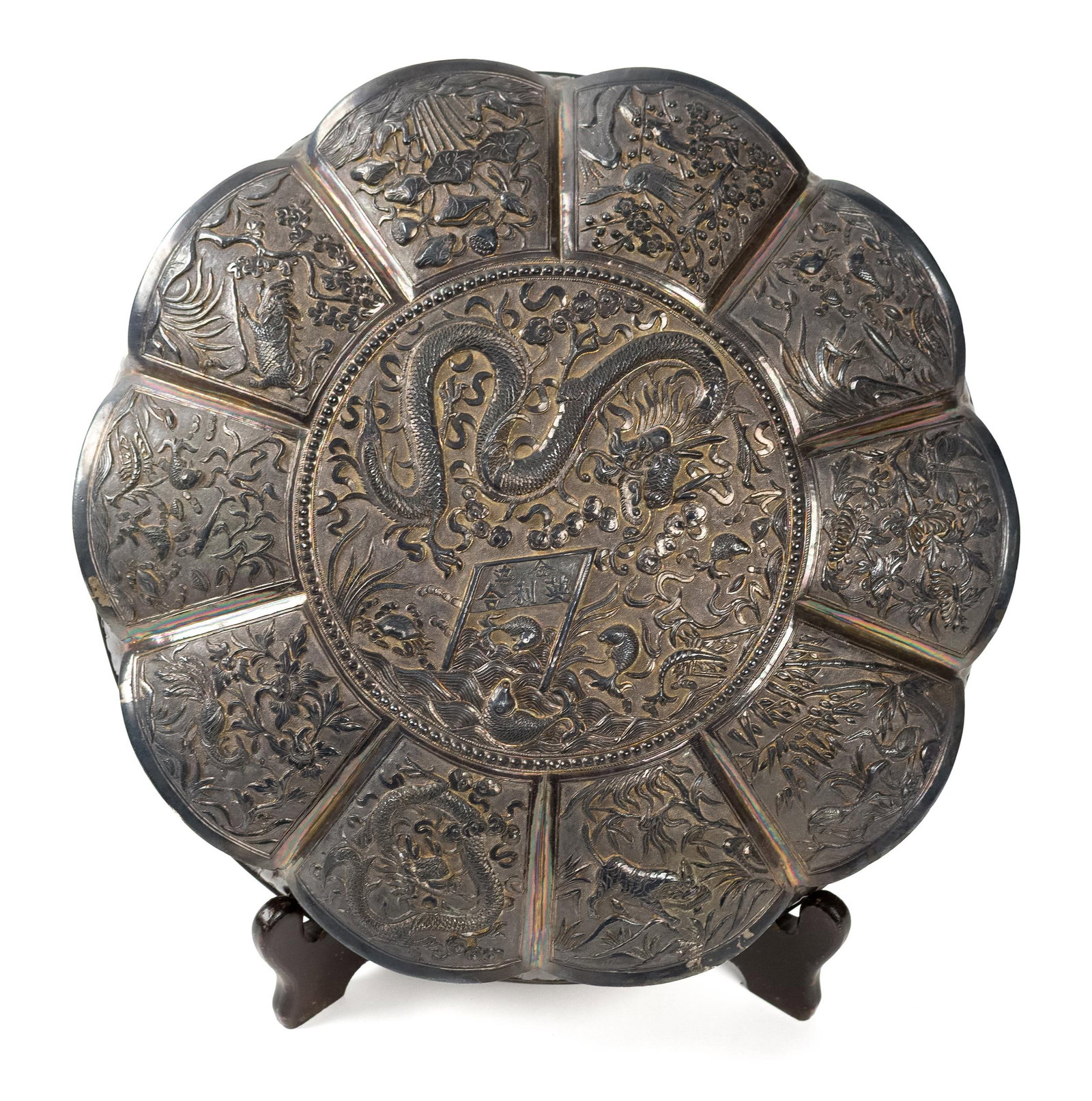 ASIAN EXPORT SILVER CEREMONIAL BOWL.: An antique Asian export silver lobed bowl of petal form, heavily repousséd overall. Decorated with radiating panels featuring dragons, a phoenix, deer, birds, and dense floral scrollwork surrounding 