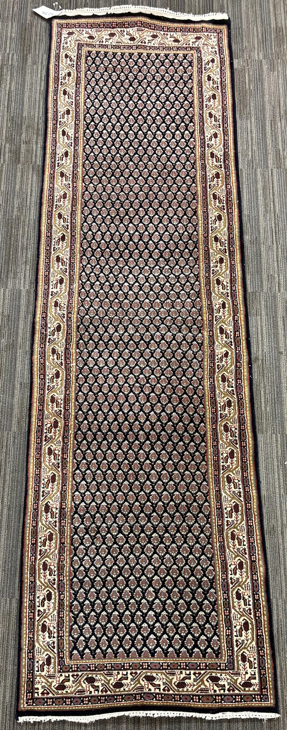 VINTAGE ORIENTAL RUNNER RUG.: A vintage Oriental runner, with a dark navy field densely patterned throughout with repeating boteh motifs in rust, ivory, tan, and muted blue. With an ivory border. 2’6” x 9’10̶