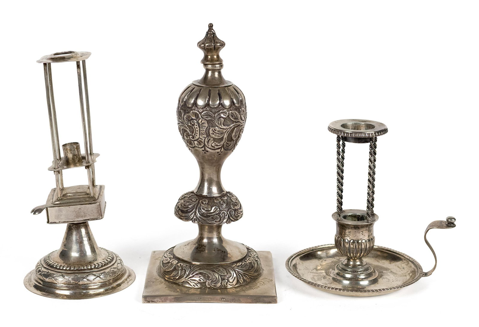 THREE SILVER JUDAICA RITUAL OBJECTS.: Three silver Judaica ritual objects, including a Havdalah candle holder with spice drawer, 8”H. Other candle holder with spiral supports, and Hebrew writing in drip tray, 6”H. An ornate