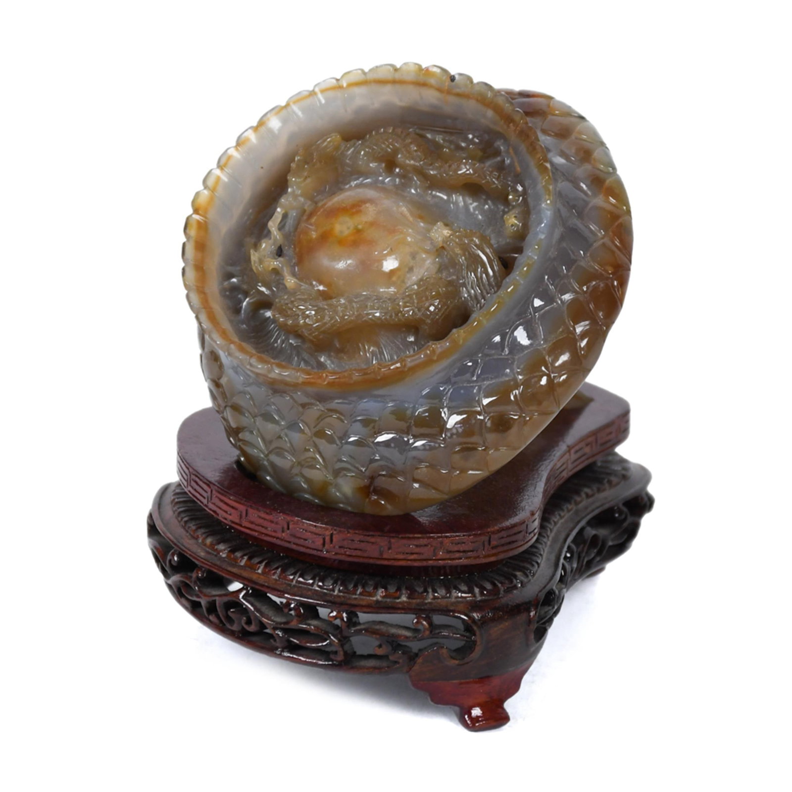 ANTIQUE CHINESE CARVED WATER AGATE DRAGON SPHERE.: A vintage grey-green Chinese water agate sphere carved in high relief with a coiling scaled dragon around the exterior and a dragon pursuing a flaming pearl in the open interior, displaying characteri