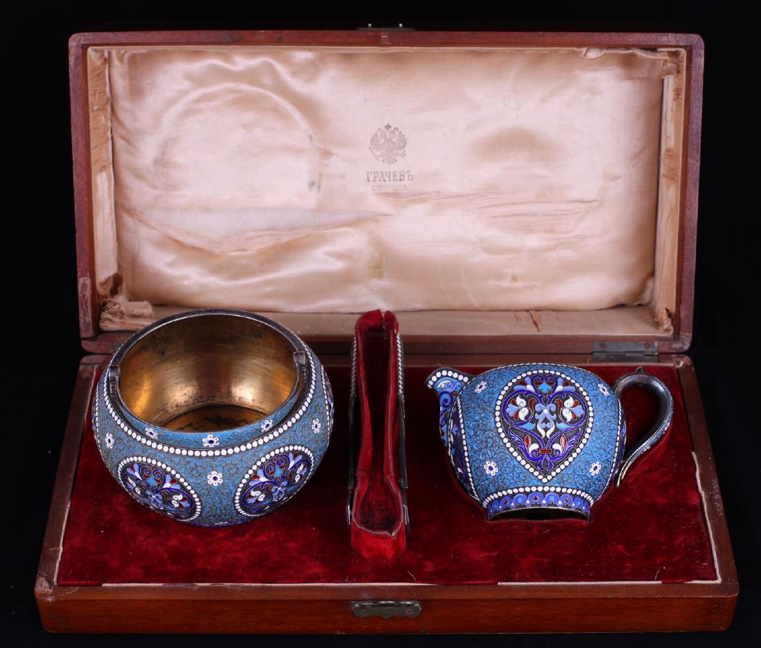 Tea set of three items. Factory Grachev brothers. 1896.: Tea set of three items. Factory Grachev brothers. 1896. St. Petersburg. The set includes a sugar bowl - 8x13 cm, a milk jug - 7x10 cm, and sugar tongs. Silver, gilding, skan', enamel. The set is place