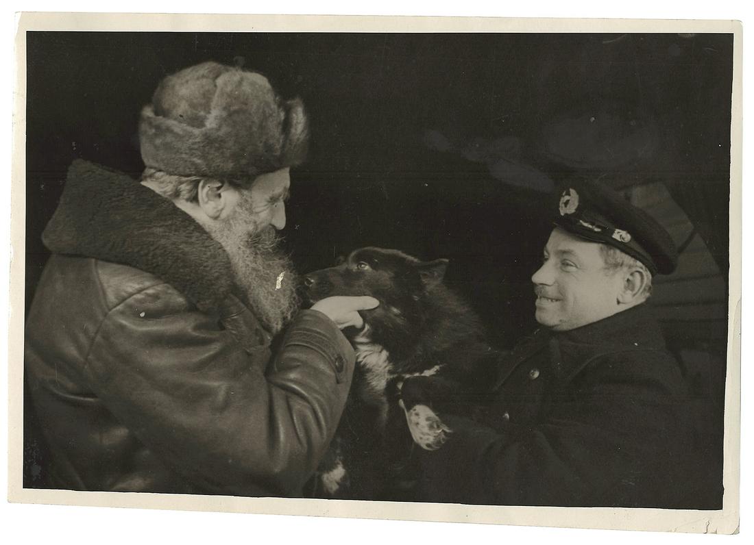 [Soviet]. Loskutov, S. Photograph "Hero of the Soviet: [Soviet]. Loskutov, S. Photograph "Hero of the Soviet Union I. Papanin is demonstrating winterer dog "Vesely" to O. Shmidt on the day of boarding of Icebreaker "Yermak". 1938. Original print. 16,5x24 