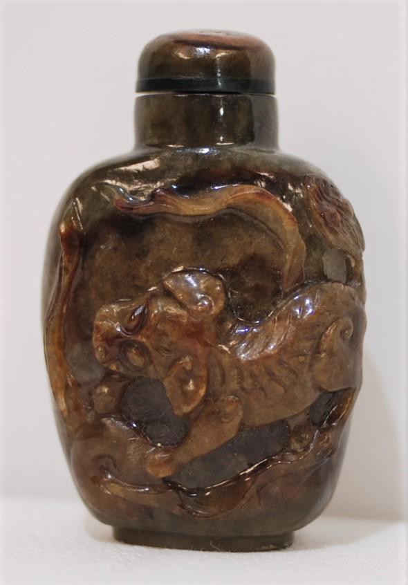 Chinese Brownish Green Unakite Snuff Bottle w/ Foo Dog: This snuff bottle is a brownish green color with a carving of a Foo Dog on the front. Unakite stopper with old spoon. 2.25 x 1.25 inches. This was purchased from Ashley Adams Inc. Naples, Florida in M