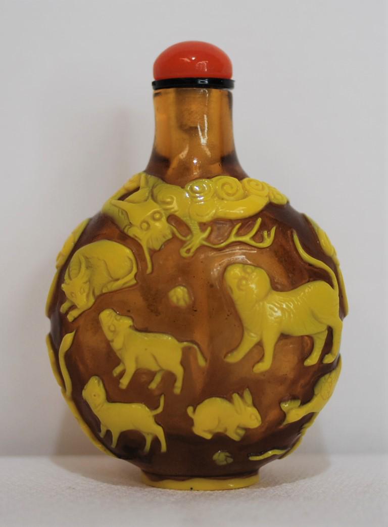 Chinese Snuff Bottle Brown Peking Glass W/ Yellow: This snuff bottle has brown peking glass with yellow overlay. Dragon circles the top, dragon handles, variety of anima figures. Globular form. Orange glass stopper. 2.5 x 1.75 inches. This was purchas
