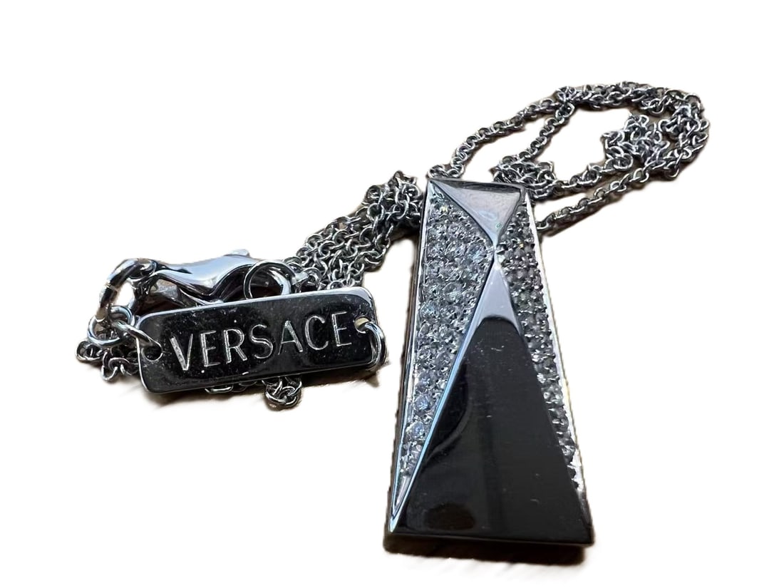 VERSACE 18 CARAT WHITE GOLD AND DIAMONDS NECKLACE WITH CHAIN: Versace 18 Carat White Gold and Diamonds necklace with chain Brand: Versace Type: Necklace Chain: with hallmarks for 18ct gold Size: Length of pendant 2.5cms. Length of chain 40cms. Accessories: N