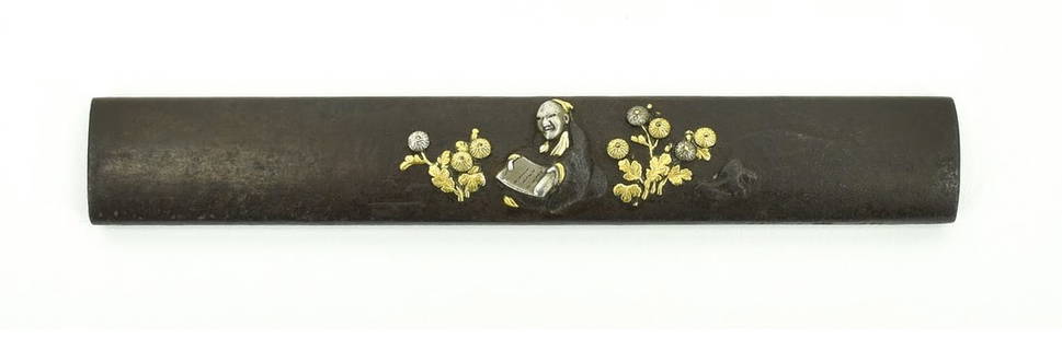 IRON KODZUKA: Iron Kodzuka Description: Iron Kodzuka. Figure with scroll amidst flowers. Shakudo, gold and silver highlights. Signed on side: Nara Toshi Haru, late 17th century. Became 3rd Nara master.  Size: None