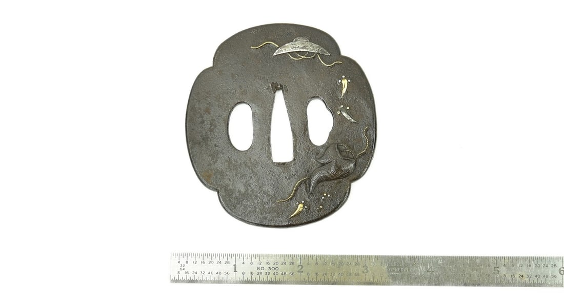 IRON TSUBA: Iron Tsuba Description: Iron Tsuba. Decorated with a silver hat with a gold cord and another device. Unsigned. Katana sized. Size: Length 3.0 inches Accessories: None Accessories Notice: When