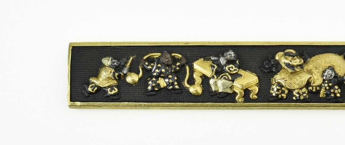 KINKO KODZUKA: Kinko Kodzuka Description: Kinko Kodzuka. Motif of Chinese boys engaging in dance with accompanying music. Gold, silver and Shakudo highlights. Shakudo Nanako ground. Reverse has gold cat-scratch