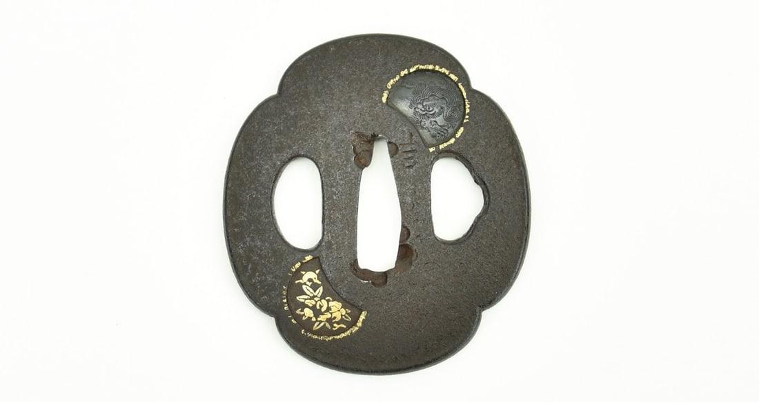 IRON TSUBA: Iron Tsuba Description: Iron Tsuba. Has Kinko insert of Shakudo Shi-Shi and 2 panels of gold foliage. Signed: first Kanji is Yoshi but following kanji is illegible. Tanto sized. Size: Length 2.25 inc