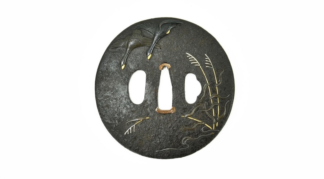 IRON TSUBA: Iron Tsuba Description: Iron Tsuba. A pair of flying Geese with gold and Shakudo highlights. Reeds with gold and copper highlights. Katana sized. Size: None Accessories: None Accessories Notice: