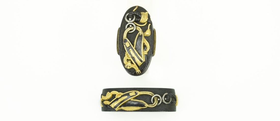 KINKO FUCHI KASHIRA AND KODZUKA SET: Kinko Fuchi Kashira and Kodzuka set Description: Kinko Fuchi Kashira and Kodzuka set. Shakudo nanako ground. Gold and shakudo cords with rings attached to a horse’s martingale. Kodzuka is