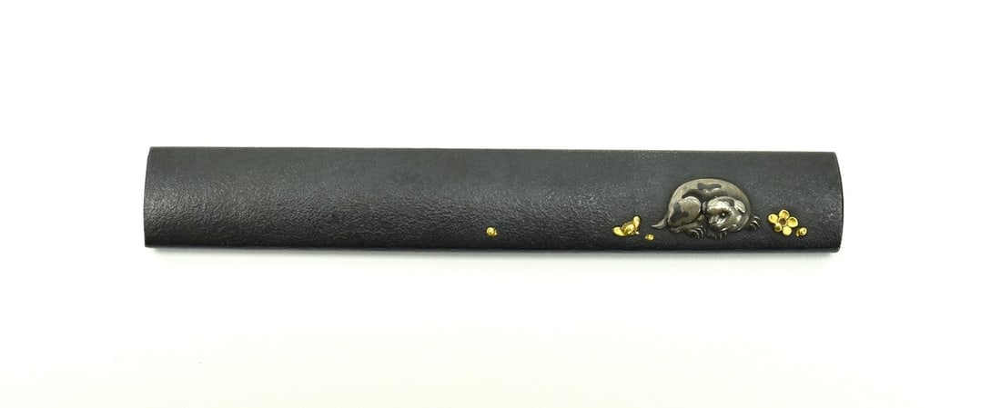 KINKO KODZUKA: Kinko Kodzuka Description: Kinko Kodzuka. Shakudo stone ground silver puppy with shakudo highlights gold flowers around the puppy. Reverse is decorated with flowers and grass. Background is