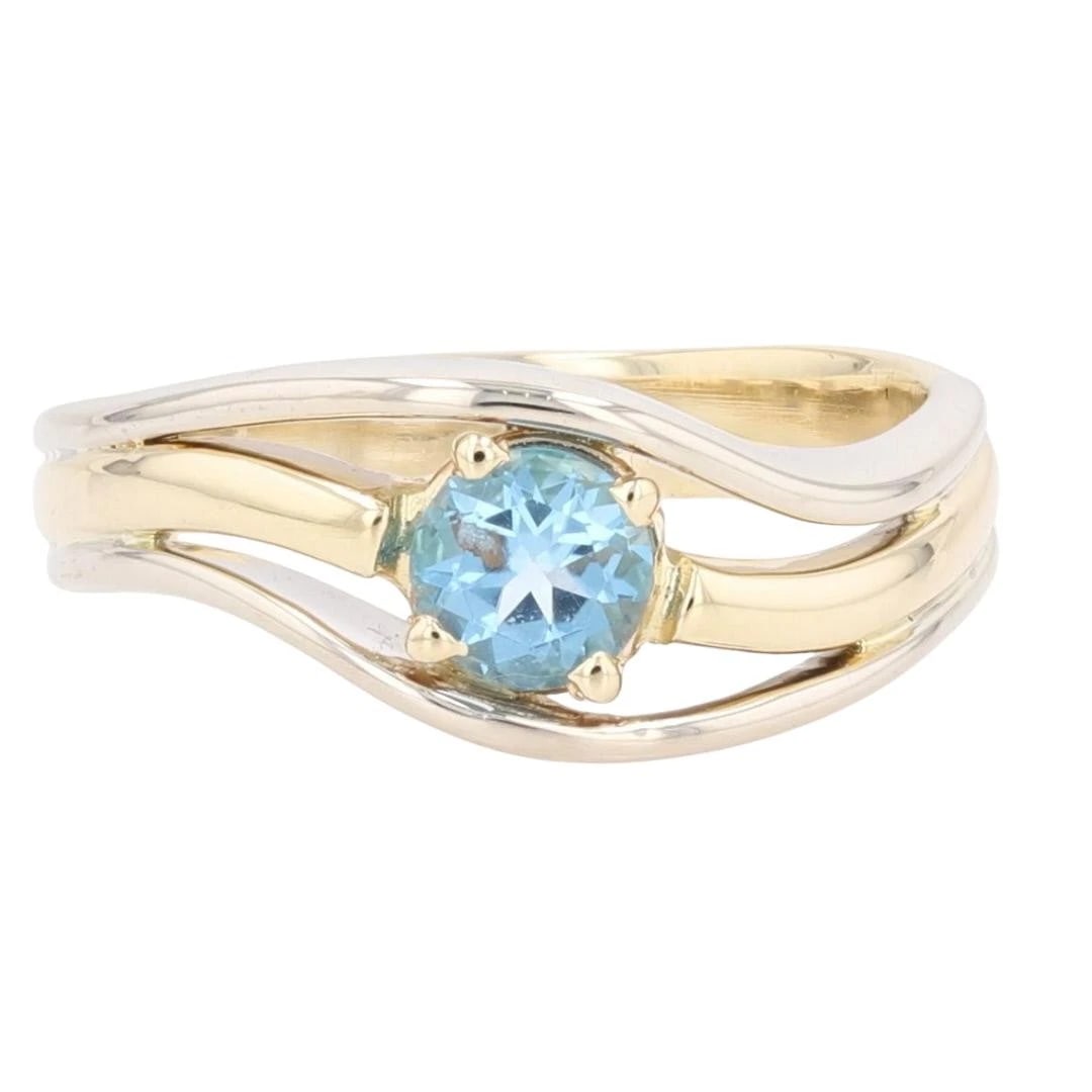 ROUND BLUE TOPAZ SOLITAIRE SPLIT SHANK RING: Round Blue Topaz Solitaire Split Shank Ring Brand: Unbranded Type: Ring Material: 10k Multi-Tone Gold Main Stone/Creation Blue Topaz Color: Main Stone Color: Medium Light Moderately Strong Very