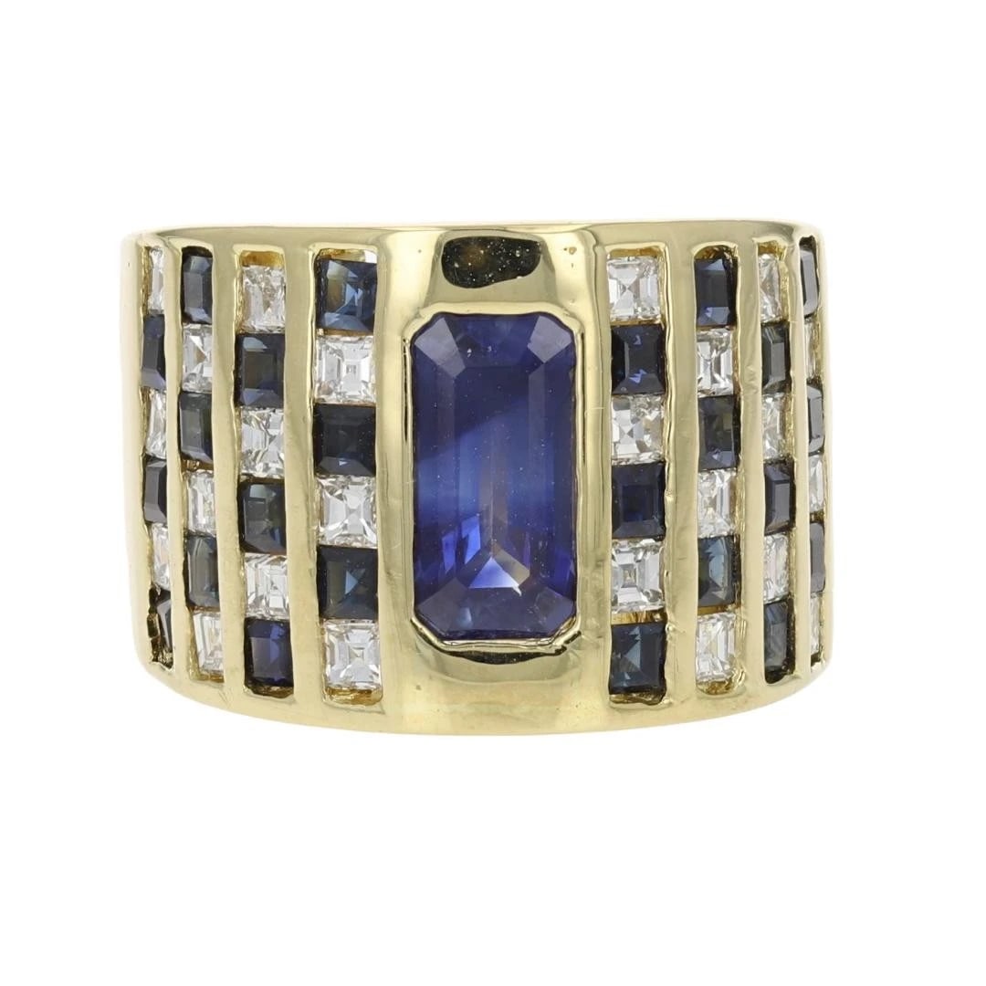EMERALD CUT SAPPHIRE WITH ACCENTS CIGAR BAND RING: Emerald Cut Sapphire with Accents Cigar Band Ring Brand: Unbranded Type: Ring Material: 18k Yellow Gold Main Stone/Creation Sapphire Color: Main Stone Color: Medium Slightly Grayish Blue Size: