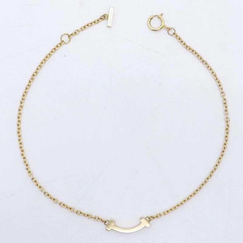 TIFFANY & CO. T SMILE MINI K18 GOLD BRACELET: Tiffany & Co. T Smile Mini K18 Gold Bracelet Brand: Tiffany & Co. Type/Style: Bracelet Material: Metal Purity K18, Metal Gold, Main Stone/Creation Natural Color: Gold Size: Wrist Circumference: Ap