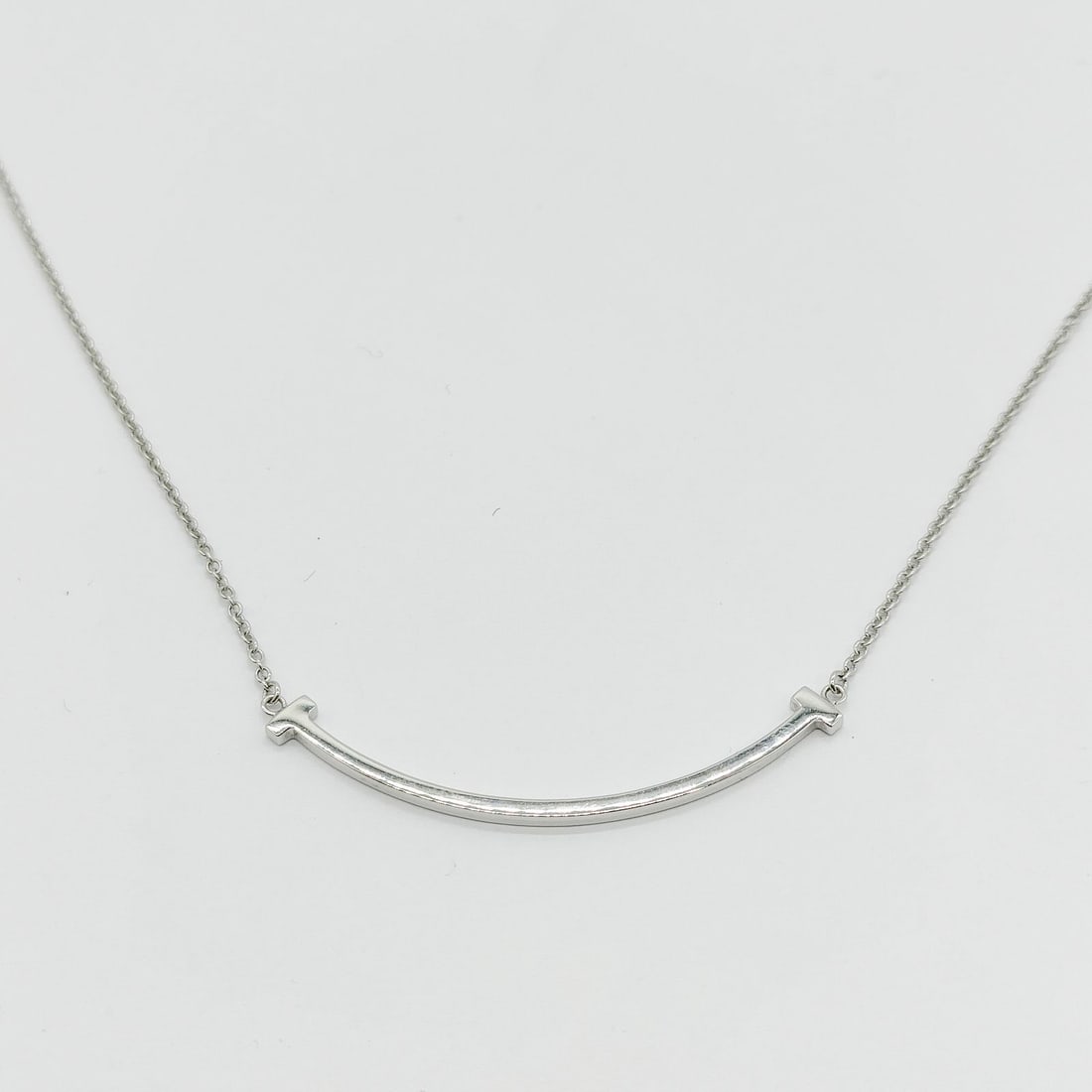 TIFFANY AND CO. NECKLACE T SMILE SMALL GOLD: Tiffany and Co. Necklace T smile small Gold Brand: Tiffany and Co. Type: Necklace Material: Gold, Color: White gold Size: Pendant Size : 0.9X3.7 cm / 0.35X1.45 inch Chain Size : 40.5 cm / 15.9 inch