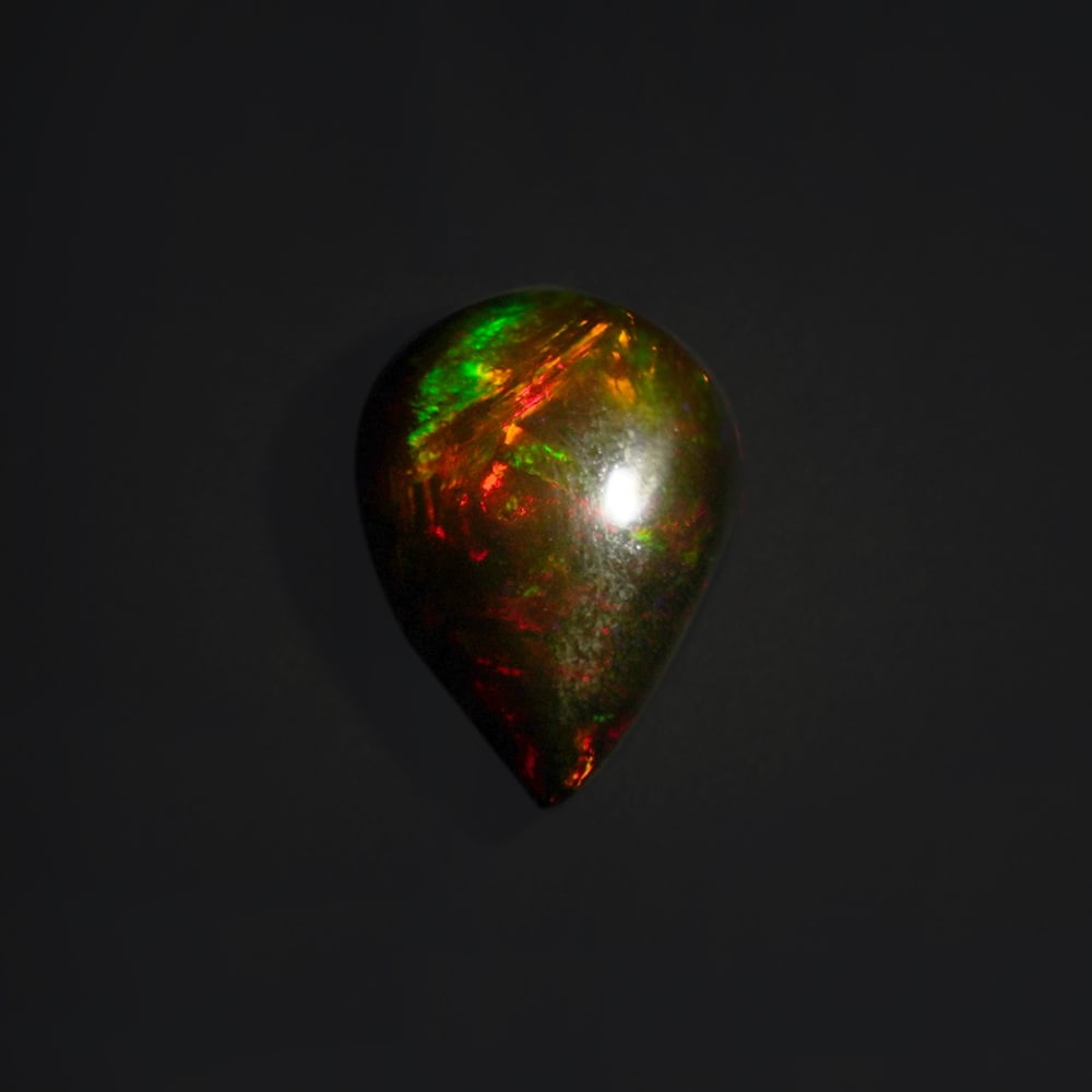 9.00 ct. Natural Play of Color Opal - ETHIOPIA: 9.00 ct. Natural Play of Color Opal - ETHIOPIA Shape - Pear Cabochon Color -Play of color Clarity - Opaque Ct. Weight - 9.00 ct. Origin - ETHIOPIA