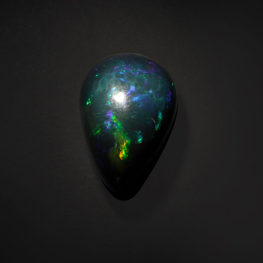 11.85 ct. Natural Play of Color Opal - ETHIOPIA: 11.85 ct. Natural Play of Color Opal - ETHIOPIA Shape - Pear Cabochon Color - Play of color Clarity - Opaque Ct. Weight - 11.85 ct. Origin - ETHIOPIA