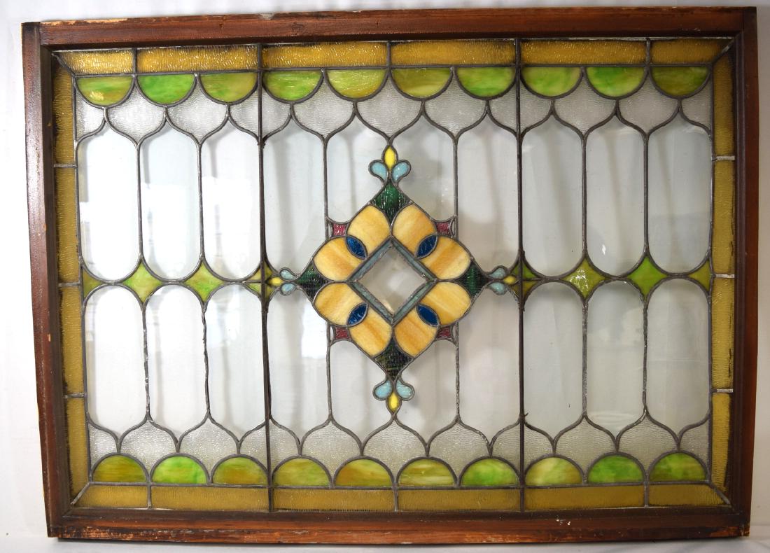 VICTORIAN LEADED STAINED GLASS WINDOW:: Medallion center in caramel, light blue, royal blue, green, red and yellow. Gothic design border and field in clear and frost glass with green and gold border. Measures 33 inches x 45 inches.
