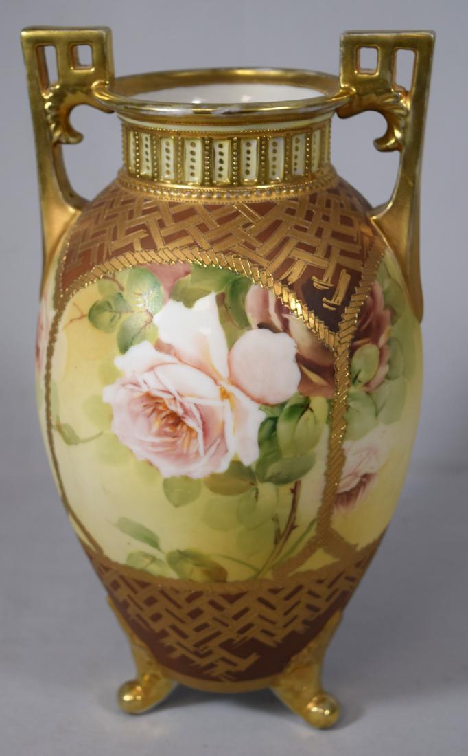 LARGE JAPANESE NIPPON PORCELAIN VASE:: Double handle and three feet with gold gilt. Panels with hand painted yellow and pink roses. Shoulder and base with geometric decoration in gold on brown ground. Vase measures 13 inches tall. Signed o