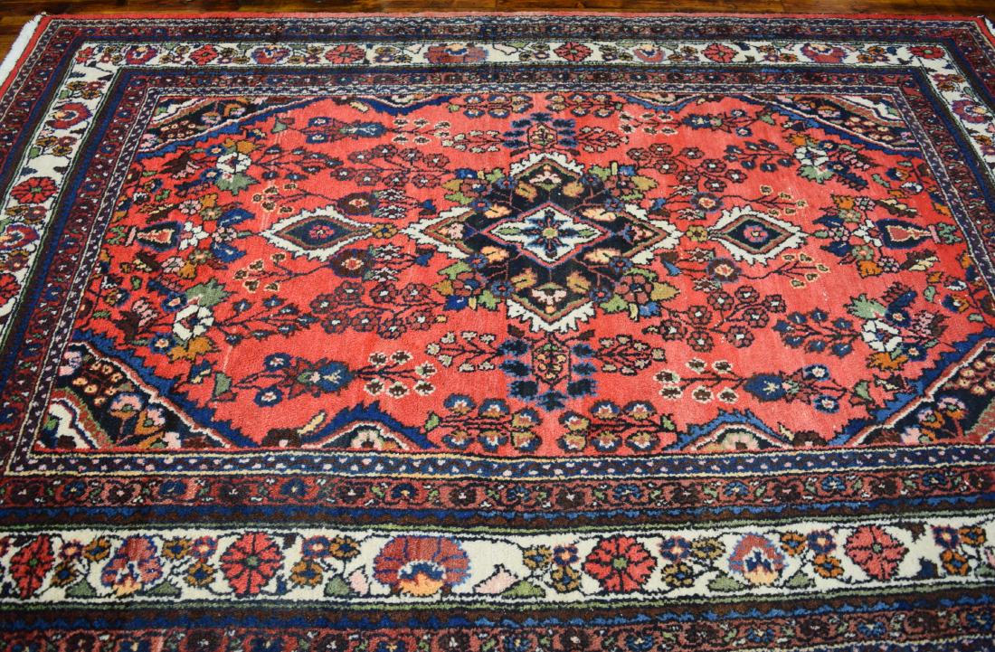 PERSIAN HAND WOVEN ORIENTAL AREA RUG:: Seven borders. Red center field with triangle center medallion. Overall floral design in blues, reds, green, pink, black, tan and cream. Measures 6 feet x 9 feet.