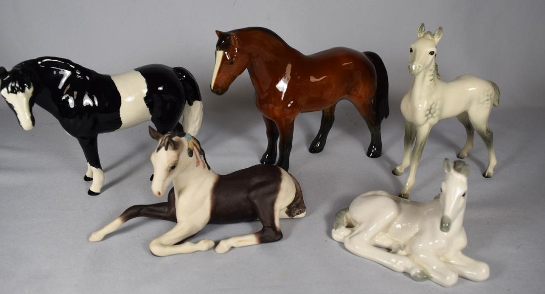 FIVE ASSORTED PORCELAIN HORSES:: Goebel gray foal, 7 ½ inches tall. Goebel Bay pony glossy, 7 ½ inches tall. Cooper Craft Pinto pony, 6 ½ inches tall. Cybis lying foal. Lomanosor lying grey foal.