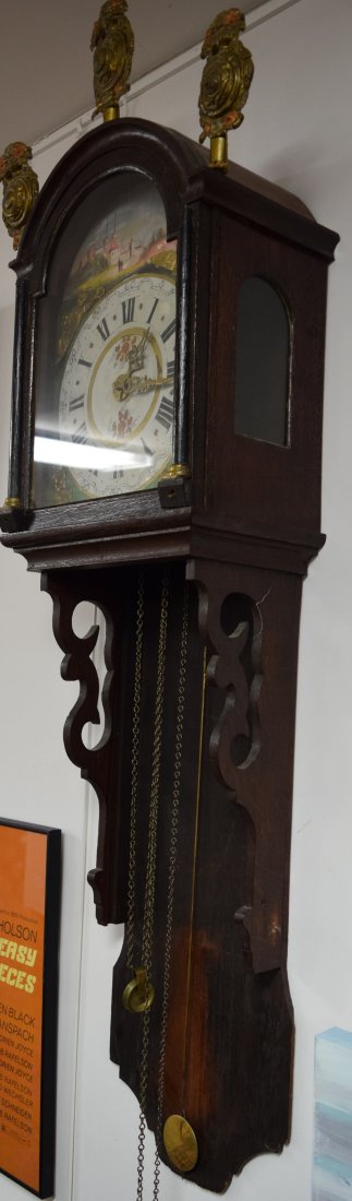 EARLY 17TH C DUTCH WAG ON THE WALL CLOCK:: Dark oak case with carved scroll sides. Sheet brass repousee finials. Hand painted iron face with European village scene, applied brass angel figures and brass hands. Brass works and weight. Face sign