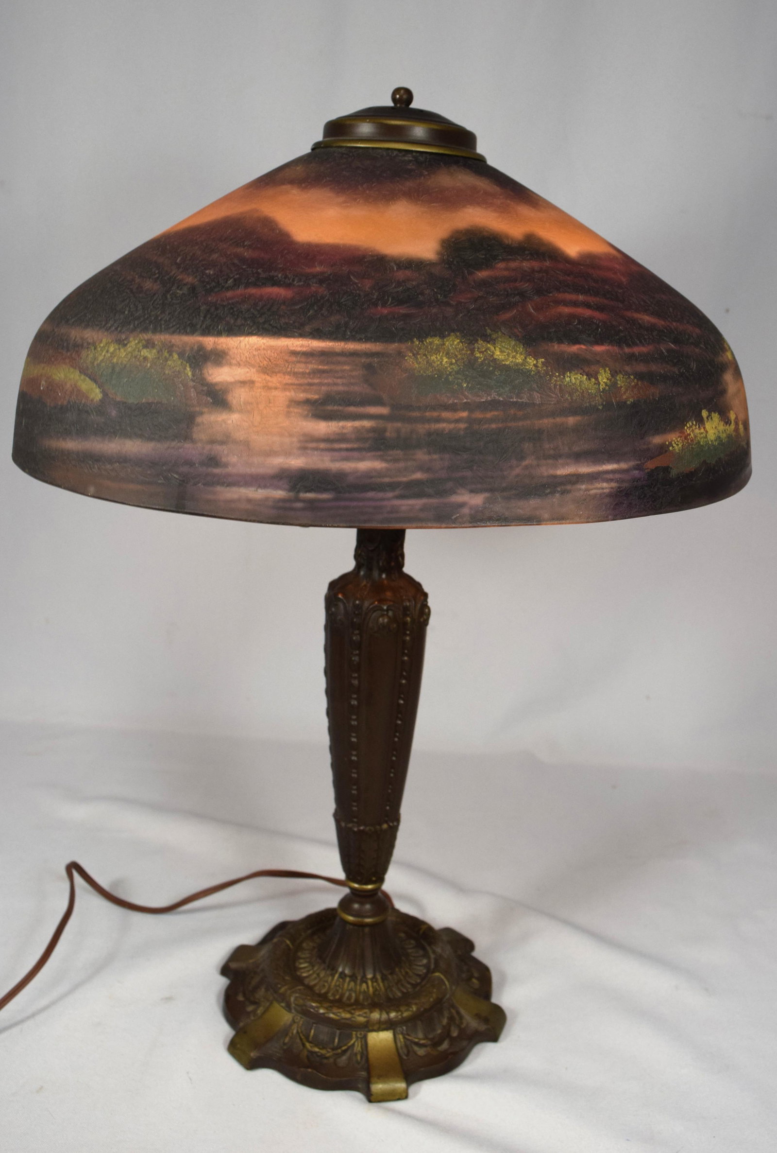PITTSBURGH REVERSE PAINTED LAKES OF KILLARNEY (IRELAND): Ca early 20th century. Chipped Ice reverse painted lamp. Mountain and lake scene painted on interior, and exterior of shade, which adds depth. Shade measures approximately 16 inches in diameter. Base 
