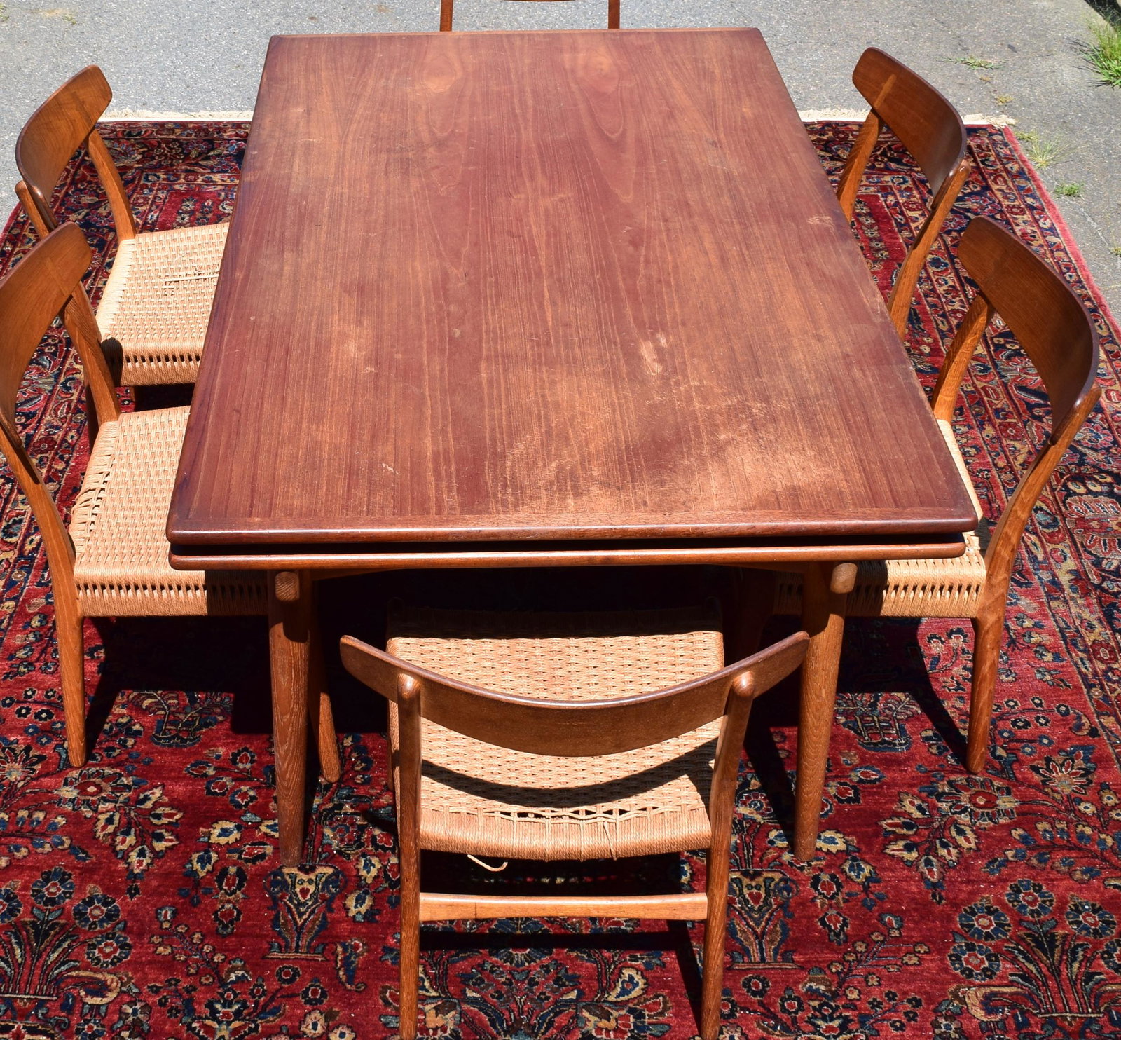 SIX HANS J. WEGNER (1914-2007). TEAK DINING CHAIRS:: Ca 1950’s/60’s. Shaped back rest with inlay. Natural fiber woven seats. Branded mark Designer Hans J. Wegner, Made by Carl Hanson & Son, Odense Denmark.
