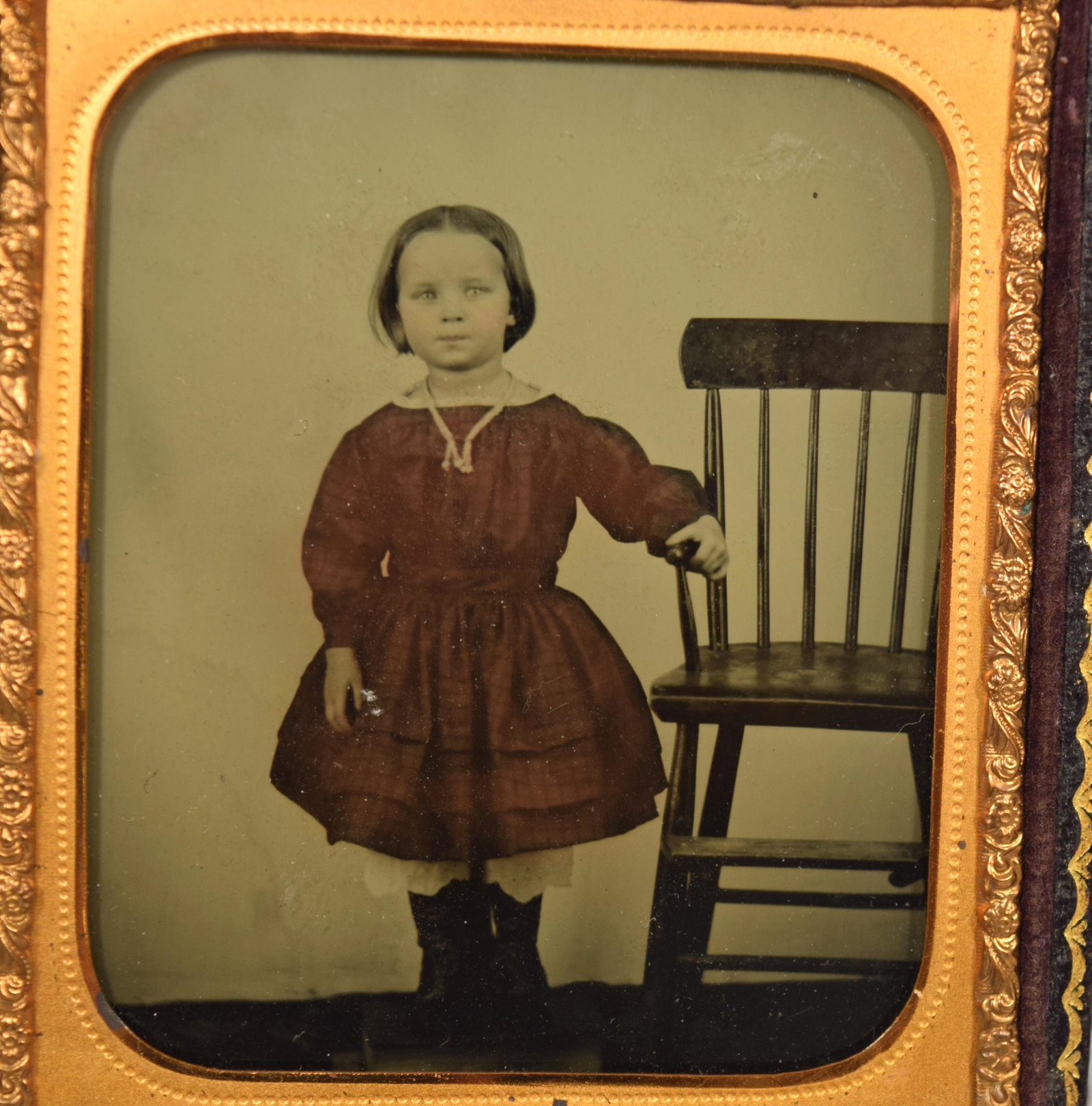 SIXTH CASED AMBROTYPE of GIRL IN RED DRESS:: Bright clean colored image of a young girl in a red dress and boots standing next to a chair. Artist unknown.