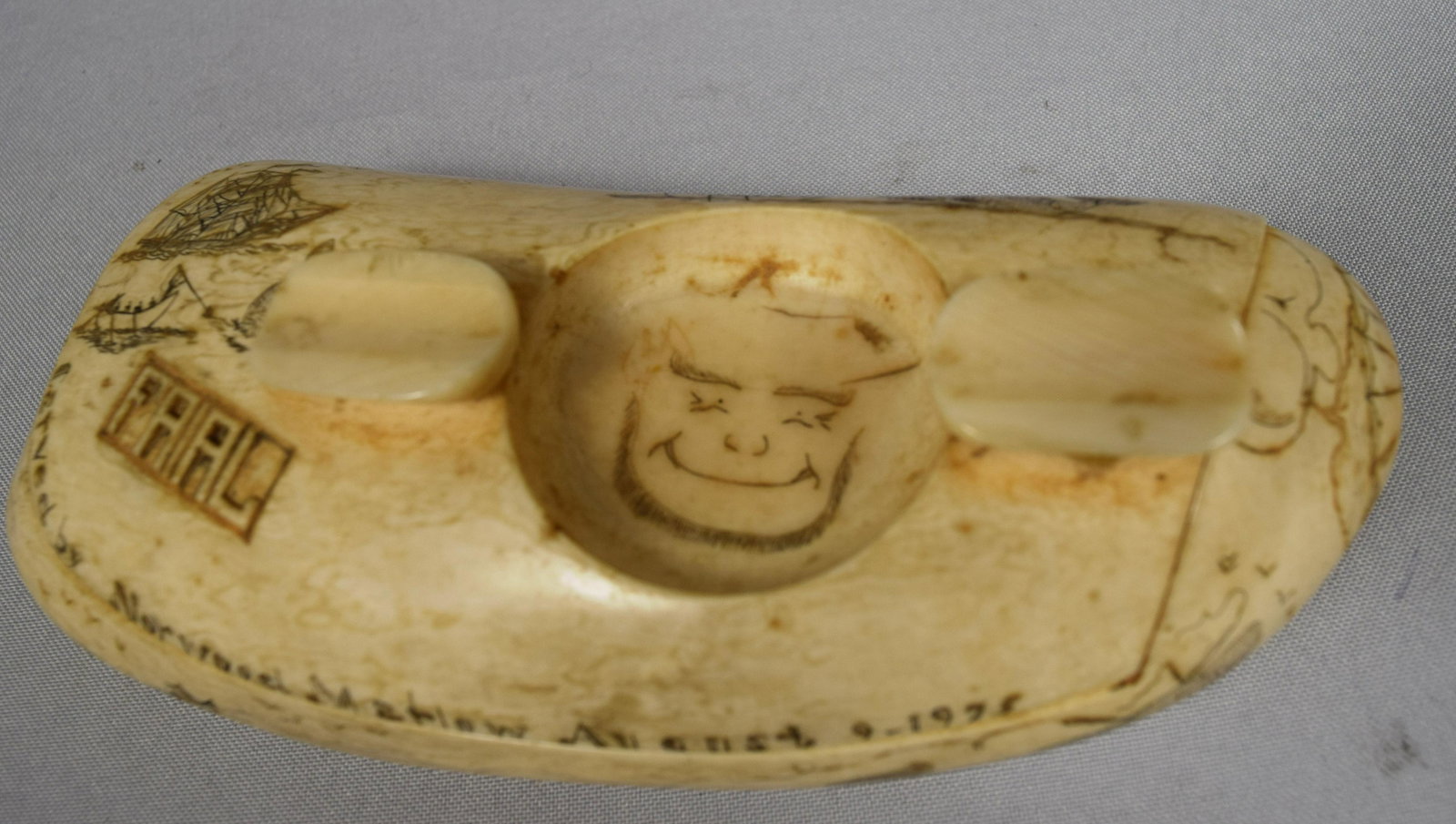 AZORES SCRIMSHAW WHALE TOOTH ASHTRAY:: Antique whale tooth with scrimshaw whaling scenes. Signed Carved by Norwood Marlow August 9, 1975.Hinged lid with small carved whale and presentation “For a long life Eddie & Toshig”. Measures 6 �
