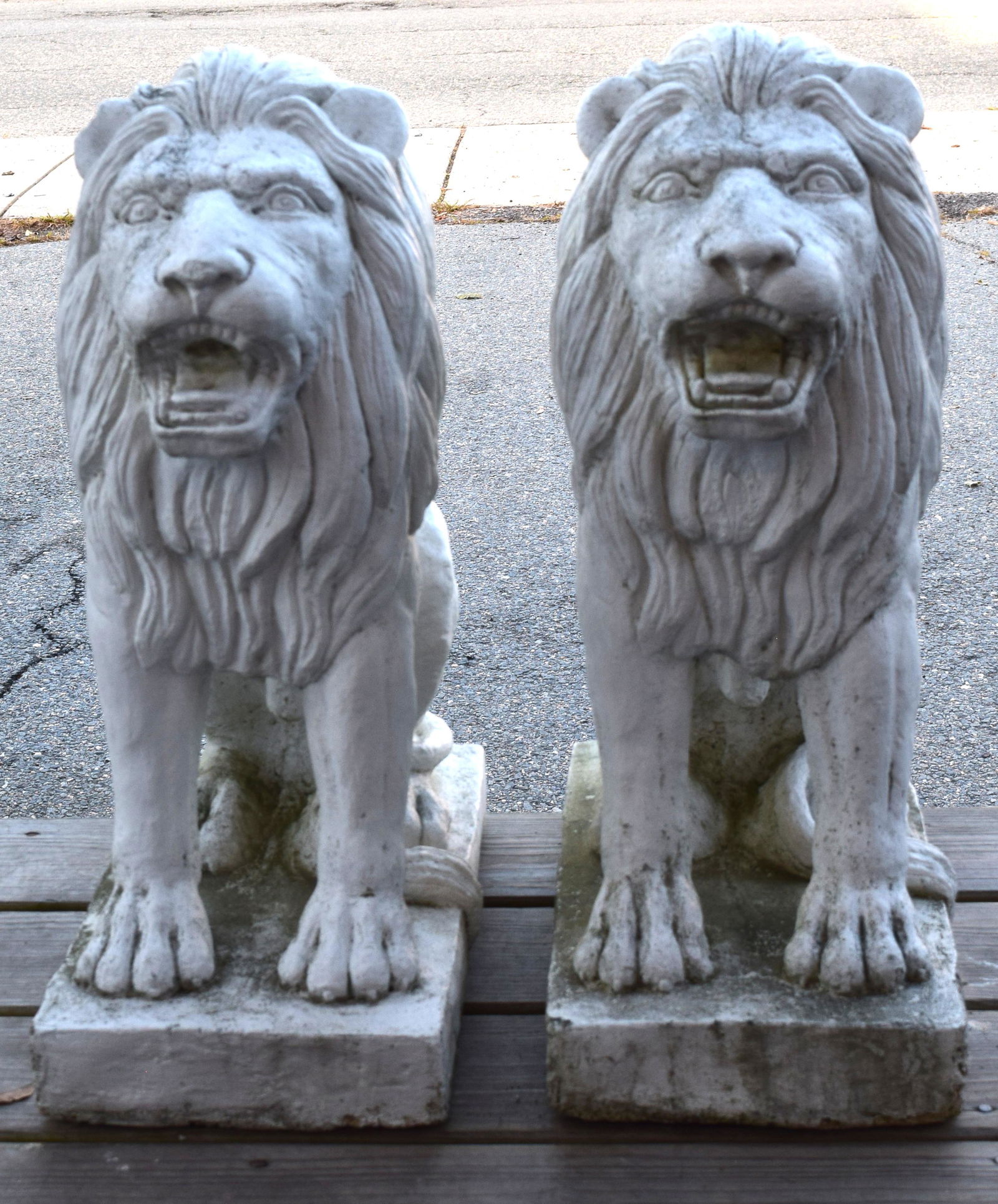 PAIR OF CEMENT SNARLING GUARDIAN GARDEN LION STATUES:: Ca early 20th century. Measure approximately 24 inches tall. Set on 9-inch x 17-inch bases. Chip on corner of one base.