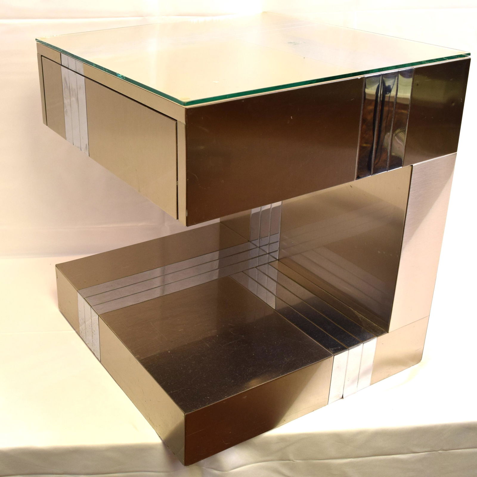 PAUL EVANS TYPE DIRECTIONAL CITYSCAPE PATCHWORK NIGHT: Ca 1970’s/80’s. Directional brass and chrome design, single drawer. In the style of Paul Evans, furniture designer (American 1931-1987). Measures 20 inches x 20 inches x 22 inches tall.