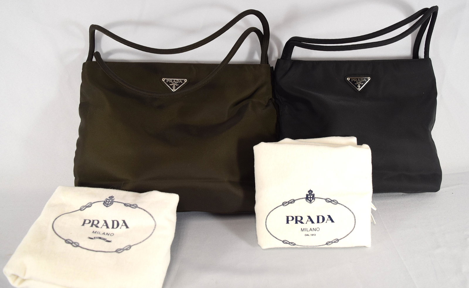 TWO VINTAGE PRADA HAND BAGS WITH DUST BAGS:: Both nylon. One black and the other dark chocolate. Both signed. Measure 13 inches x 10 inches.