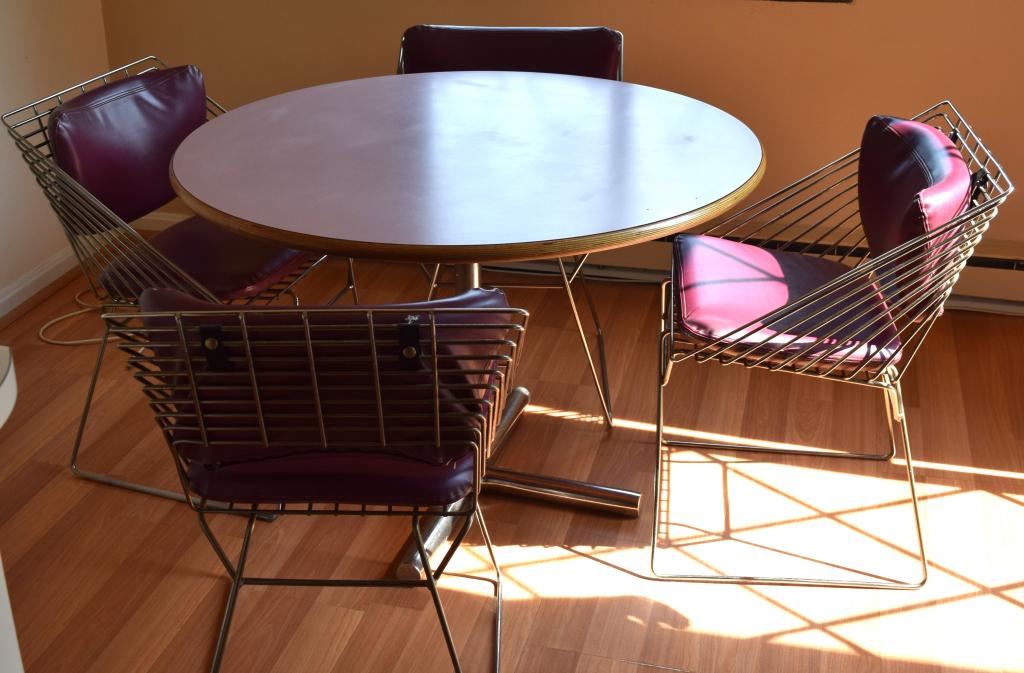 MODERNIST STYLE KITCHEN TABLE & CHAIRS:: Round formica top kitchen table, oak rim, chrome tri-pod base. Measures 42 inches in diameter x 29 inches tall. With four heavy chrome dining chairs. Back with open chrome ribs, two eggplant color vin