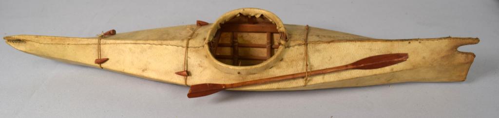 SEAL SKIN ESKIMO INUIT KAYAK: Norton Sound Alaska. Measures 21 1/2 inches long. Wooden and seal skin kayak model. Original condition with accents. Paddle has loss at one end. Good condition.