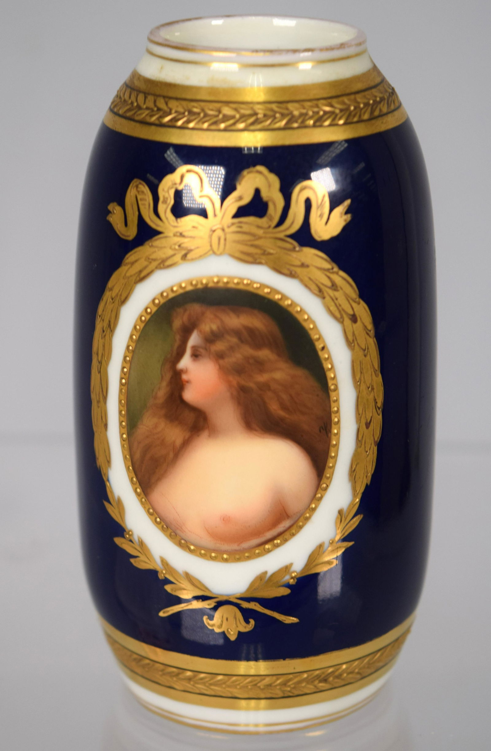 KPM GERMANY PORCELAIN TYPE VASE: Hand painted cameo wreath with Erbluht semi-nude bust. Cobalt blue with gold painted high lights. Measures 4 ½ inches tall. Signed and marked made in Germany on base. Good condition.