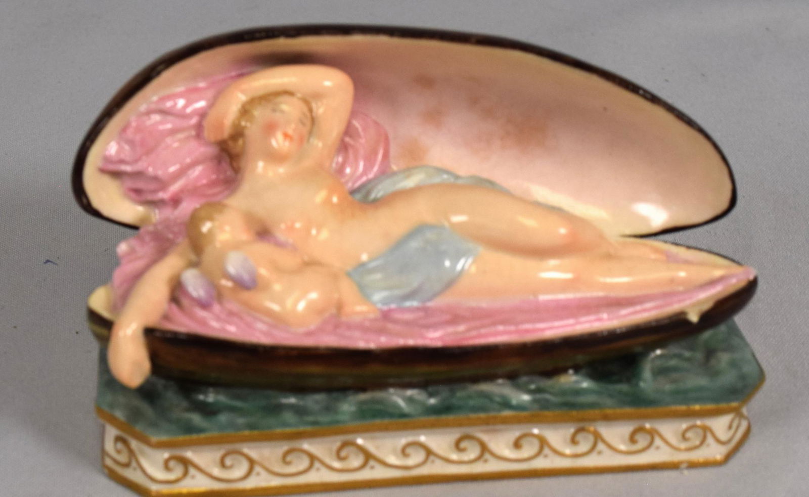 GERMAN MEISSEN FIGURINE VENUS & CUPID: 19th/20th Venus and cupid porcelain group in shell. 5 inches long x 2 3/4 inches tall. Marks on base. Chipped.