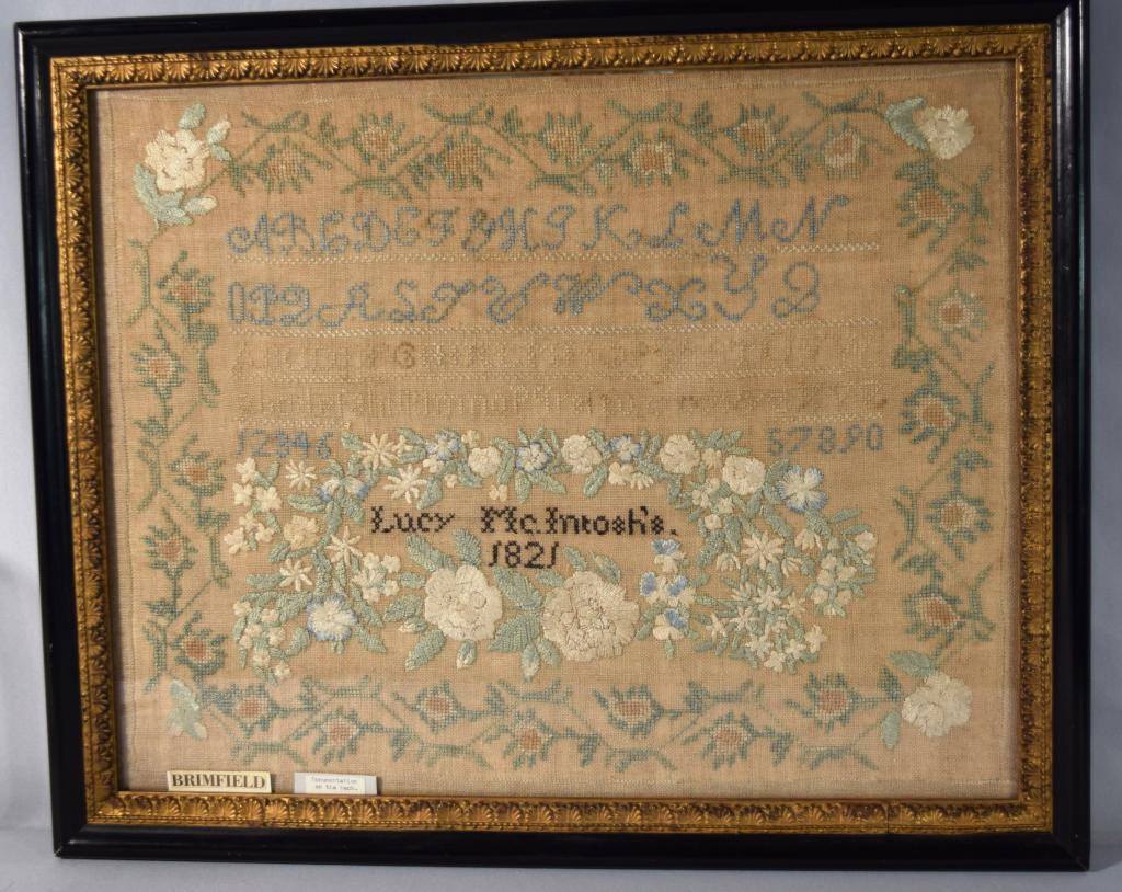 BRIMFIELD MA 1821 SAMPLER: Lucy McIntosh, aged seven, dated 1821. A floral border on four sides enclosing three alphabets in different sizes and numerals 1 to 10. Below is a laurel of silk flowers with the name Lucy McIntosh an