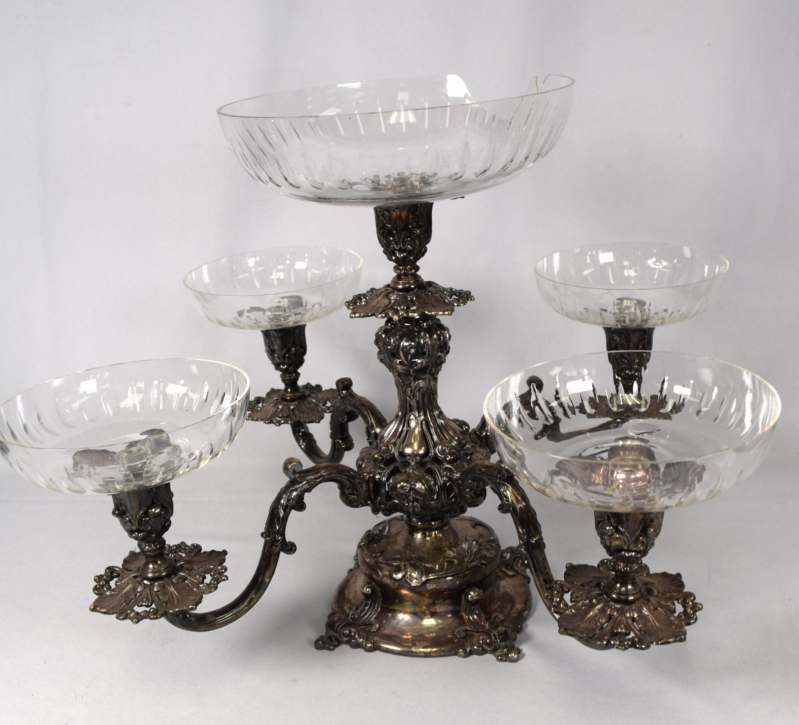 VICTORIAN SILVERPLATE & GLASS CENTER EPERGNE: Fancy Victorian silverplate & glass dish or candle holder arms. 14 1/2 inches tall x 22 inches wide. Repoussee scrolls, leaf designs. Top dish damaged.