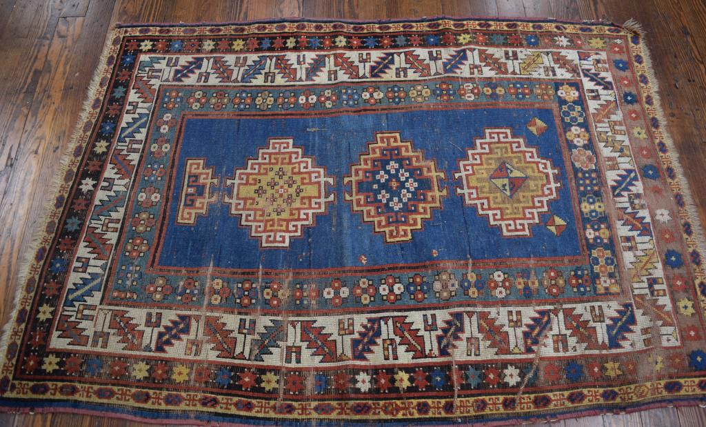 CA 1870'S EARLY KAZAK SCATTER RUG:: Blue center field with three geometric and ram's head medallions. Wide sawtooth and wine cup border on cream ground, three additional borders. Colors of blues, reds, rust, greens, gold, cream and blac