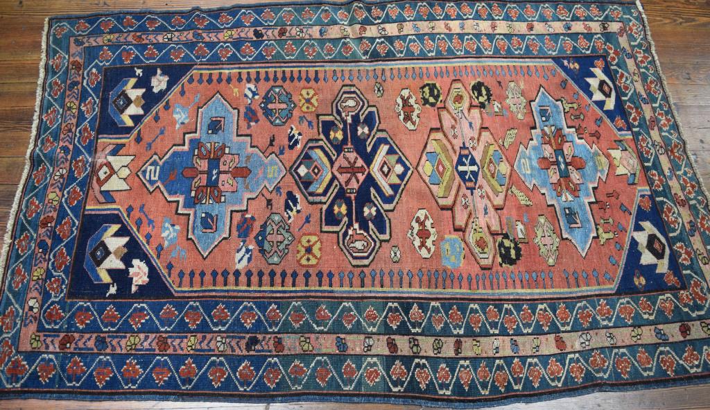 ANTIQUE CAUCASIAN KUBA AREA RUG:: Ca 1880's. Large salmon center field with four multi color geometric medalions. three borders. Measures approximately 77 inchs x 48 inches. Colors of salmon, blues, greens, reds, pink, gold, tan and c