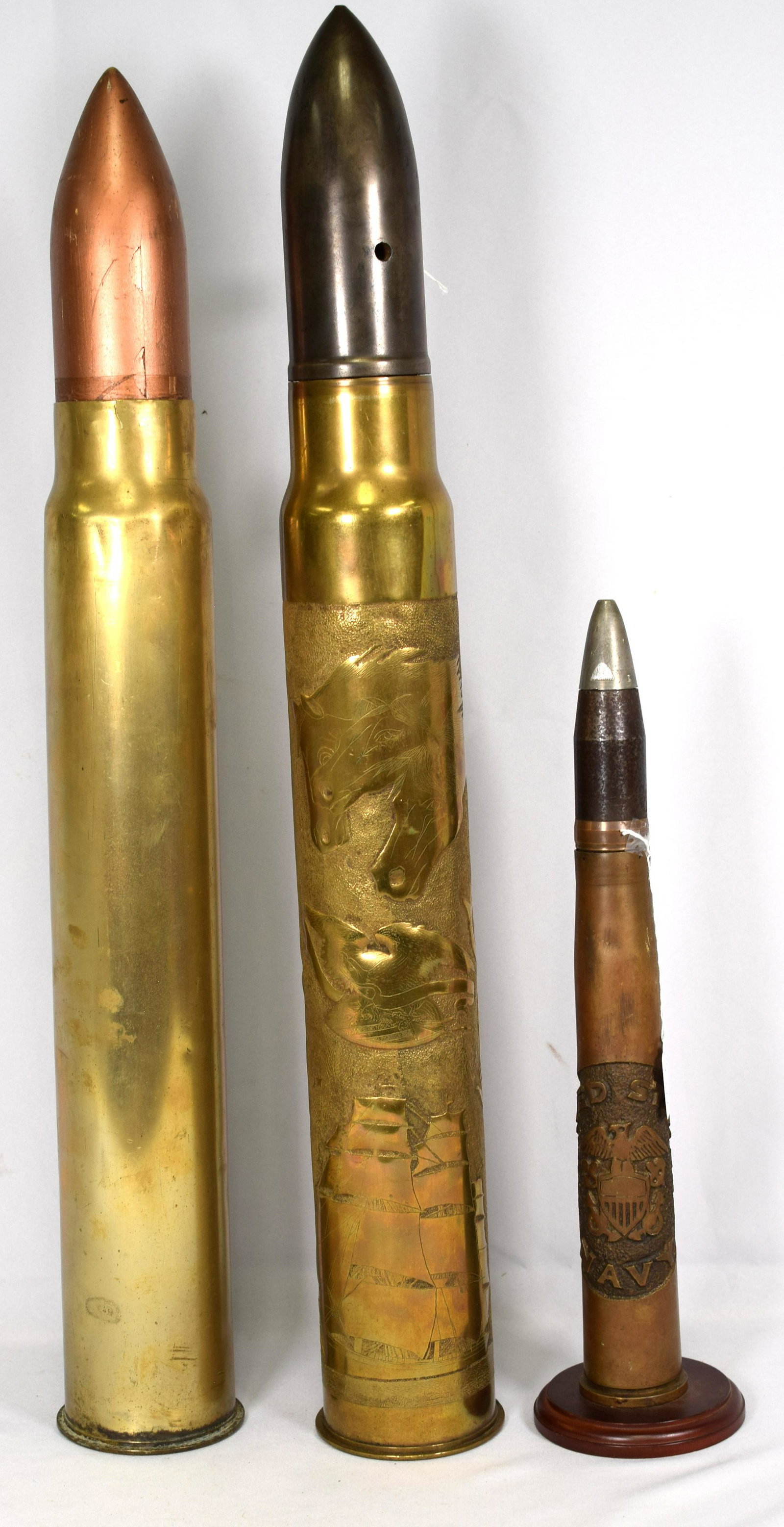 (3) WW1 MILITARY SHELLS: 2 shells have trench art, 1) The smallest one is United States Navy with the name and eagle design on it, 18 1/2 inches in height 2 1/2 inches diameter. The other shell with trench art features many d