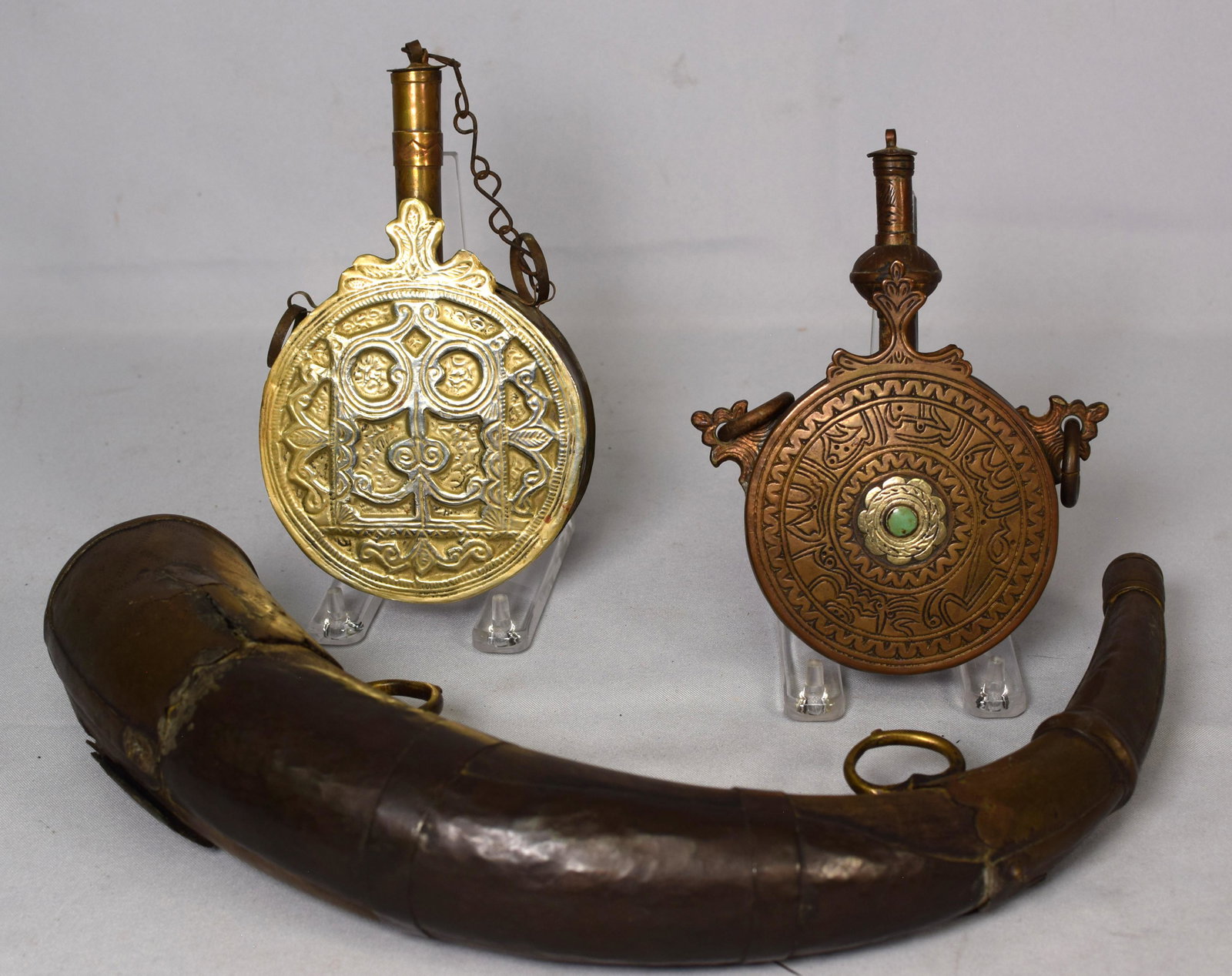 (3) ISLAMIC OTTOMAN POWDER FLASKS & POWDER HORN: Lot consists of three items. 1) 18th/19th century. Disk shape in brass with decoration. Largest 7 inches x 4 1/4 inches. Small one 6 1/4 inches x 3 3/4 inches. Coral and turquoise accents. Goodconditi