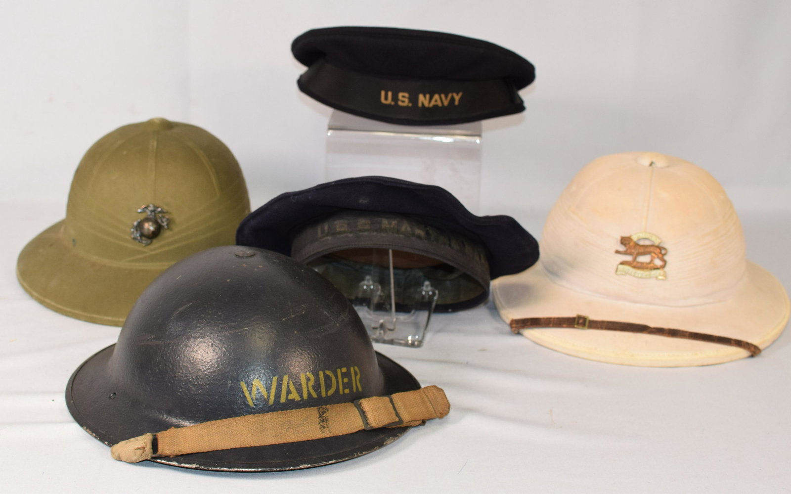 (5) MILITARY HATS, HELMET AND CAPS: Grouping consists of five items. 1) USN WWII Pith. Good condition. 2) British Hindoostan Military pith. Good condition. 3) World War II british air raid helmet. Dark green with original scrap. Good co